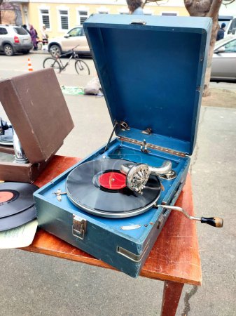 An old retro record playing on old vintage gramophone at flea market. Work of portable gramophone. Old vintage shabby record player, phonograph, potefone. Needle. Nostalgia antique audio turntable
