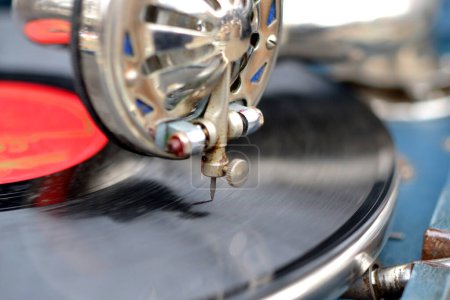 Eine alte Retro-Platte spielt auf einem alten Vintage-Grammophon auf dem Flohmarkt. Arbeit mit tragbarem Grammophon. Alter, schäbiger Plattenspieler, Phonograph, Telefon. Nadel aus nächster Nähe. Nostalgie-Drehscheibe