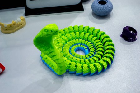 Das grüne Schlangenspielzeugmodell wurde auf einem 3D-Drucker aus geschmolzenem Plastik gedruckt. Schlangenförmiges Objekt aus dem 3D-Drucker. Detaillierter grüner Prototyp, gedruckt auf 3D-Drucker aus nächster Nähe. Neue moderne additive Technologien