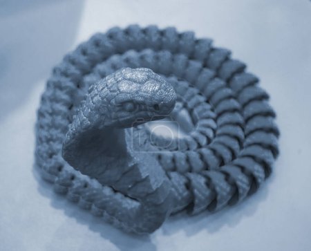 Schlangenspielzeugmodell gedruckt auf einem 3D-Drucker aus geschmolzenem Plastik. Schlangenförmiges Objekt aus dem 3D-Drucker. Detaillierter grüner Prototyp, gedruckt auf 3D-Drucker aus nächster Nähe. Neue moderne additive Technologien