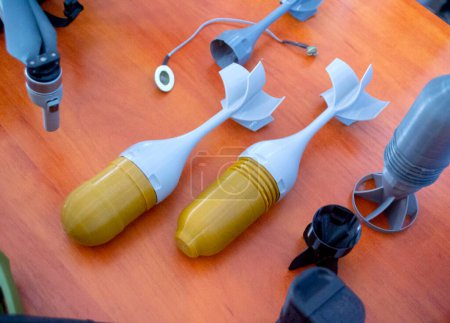 Foto de Modelo prototipo de punta de bomba cohete impreso en impresora 3D. Pequeños modelos de aletas de cola, cono de cola impreso en la impresora 3D de plástico fundido. Armas militares. Nueva tecnología de impresión de innovación moderna - Imagen libre de derechos