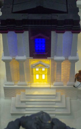 Prototipo impreso en el edificio de ladrillo de la impresora 3D con columnas y ventanas brillantes. Modelo de construcción con color blanco y marrón, ventanas con luz brillante, creado por la impresora 3D de plástico fundido