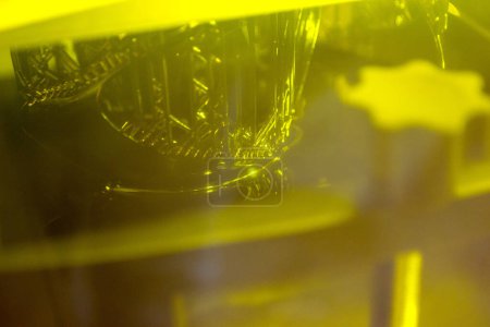 Working of photopolymer sla 3D printer. Platform with building object lowered into liquid photopolymer resins and hardened under ultraviolet laser. Progressive additive technology. 3D printer printing