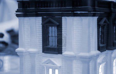 Modell des Gebäudes mit weißer und schwarzer Farbe, Fenster mit leuchtendem Licht, hergestellt im 3D-Drucker aus geschmolzenem Kunststoff. Prototyp gedruckt auf 3D-Drucker Backsteingebäude mit Säulen und glühenden Fenstern.