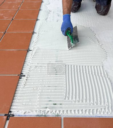 Téléchargez les photos : Worker spreads the cement glue before applying the ceramic tiles - en image libre de droit
