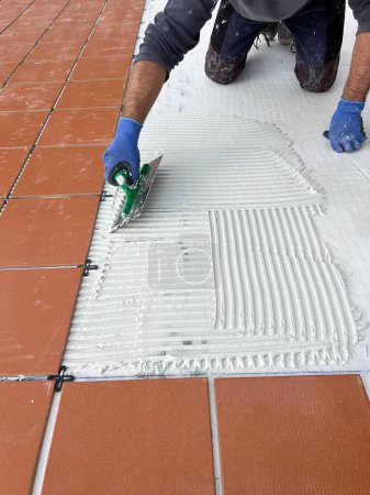 Téléchargez les photos : Worker spreads the cement glue before applying the ceramic tiles - en image libre de droit