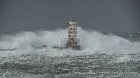 Foto de The lighthouse of the mangiabarche in calasetta, in southern sardinia, submerged by the waves of the stormy sea - Imagen libre de derechos