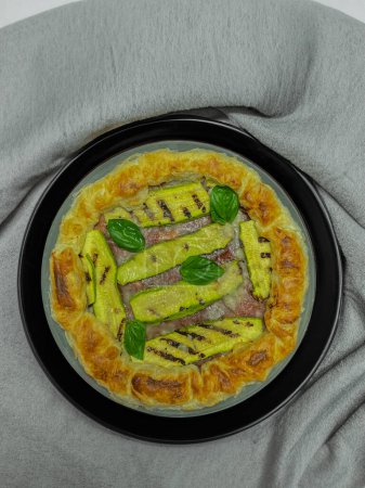 Foto de Pastel salado con calabacines y albahaca en un plato redondo - Imagen libre de derechos