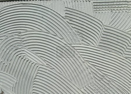 Cemento adhesivo cementoso de pared aplicado al suelo.Fondo gris moderno con líneas curvas
