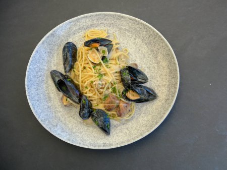 Traditional Italian seafood pasta with clams, mussels, bottarga and parsley in white plates