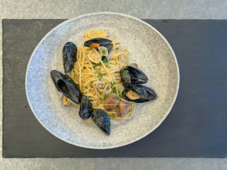 Traditional Italian seafood pasta with clams, mussels, bottarga and parsley in white plates