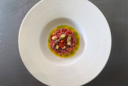 Modern style gourmet raw beef fillet tartare with cappei egg and dried tomato