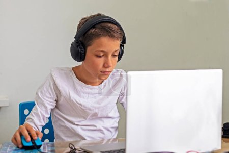 teenage boy sits in headphones at a computer at home.Children and gadget