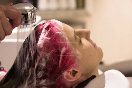 Foto de Close-up of a barbershorper washing her head with a happy teenage girl with pink hair - Imagen libre de derechos