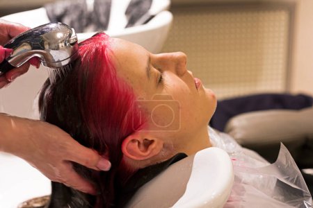 Téléchargez les photos : Barbershorper washes pink dye from hair of a teenage gir - en image libre de droit