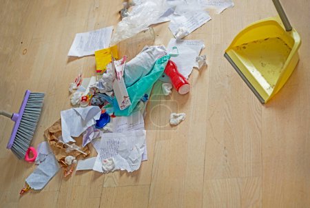 Foto de Adolescente limpia la basura en su habitación con una escoba y un cubo de basura en el parquet - Imagen libre de derechos