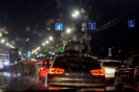 Photo for Traffic jam on the road late in the evening during a downpour in the capital of Ukraine, Kyiv. Bad weather. War in Ukraine - Royalty Free Image