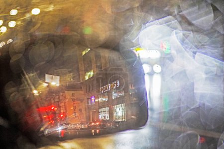 Téléchargez les photos : Abstrait fond flou de gouttes de pluie floues sur le miroir gauche d'un embouteillage de voiture dans la ville. Mauvais temps - en image libre de droit