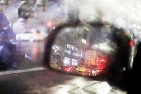 Téléchargez les photos : Fond flou abstrait de gouttes de pluie floues sur le miroir gauche d'un embouteillage de voiture dans la ville. - en image libre de droit
