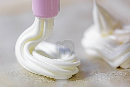 Foto de Preparar merengue clásico con una jeringa de pastelería en casa. Humor festivo - Imagen libre de derechos