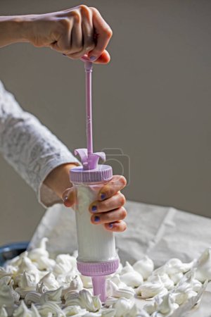 Téléchargez les photos : Mains d'une petite fille préparer une meringue classique avec une seringue à pâtisserie. - en image libre de droit