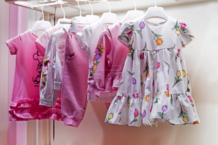 Téléchargez les photos : Robes d'été pour enfants mignons avec des imprimés floraux sur un cintre, horizontal - en image libre de droit