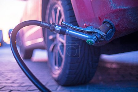 Photo for Close-up refueling a red car at a gas station at sunset, economics - Royalty Free Image