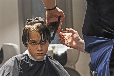 Téléchargez les photos : Salon de coiffure coupe les extrémités des cheveux propres humides à un garçon avec des ciseaux - en image libre de droit