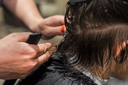 Téléchargez les photos : Barbier coupe les pointes de cheveux propres humides à l'arrière de la tête du garçon avec des ciseaux - en image libre de droit