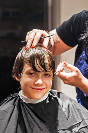 Téléchargez les photos : Salon de coiffure coupe les extrémités des cheveux propres humides à un garçon avec des ciseaux - en image libre de droit