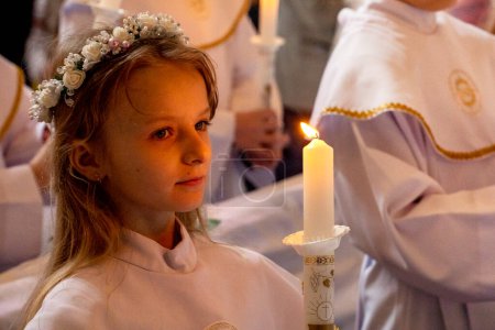 Photo for Girl in an alba with a burning candle at the first communion. first communion - Royalty Free Image