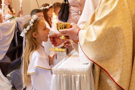 girl in an alba with a burning candle takes the first communion. first communion