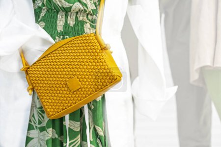 Photo for Yellow fashionable woven clutch bag on a chintz green dress. Fashion everyday - Royalty Free Image