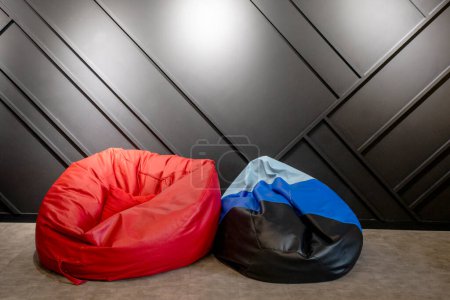 Téléchargez les photos : Fauteuil bleu et rouge sans cadre près d'un mur moderne sombre dans le bureau. maquette intérieure - en image libre de droit