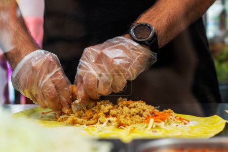 Photo for Male hands in disposable gloves prepare a vegetarian shawarma. street food - Royalty Free Image
