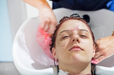 Gesicht eines Teenagermädchens mit Problemhaut wäscht sich vor einem Haarschnitt in einem Schönheitssalon die Haare