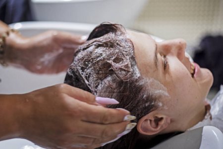 Hände eines Friseurs waschen den Kopf eines Teenagers Mädchen nach dem Färben in einem Schönheitssalon