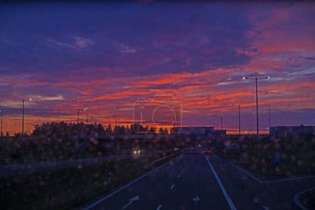 Téléchargez les photos : Lever de soleil flou sur l'autoroute à travers le verre sale du bus. - en image libre de droit