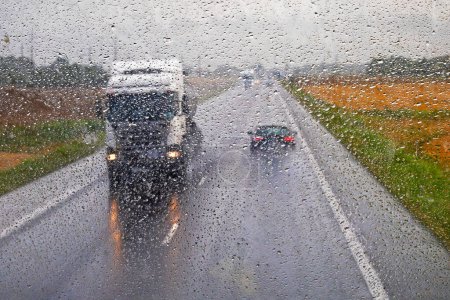 Téléchargez les photos : Camion conduit sur la route principale glissante sous la pluie. Mauvais temps - en image libre de droit
