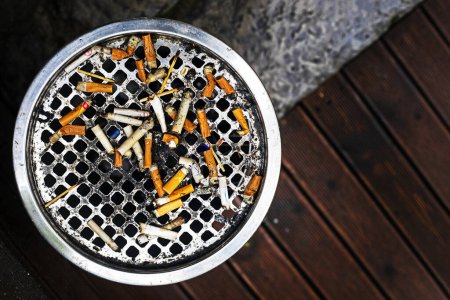 Foto de Muchas colillas de cigarrillos en un cenicero afuera. Flatlay. Los cigarrillos y fumar son perjudiciales para la salud - Imagen libre de derechos