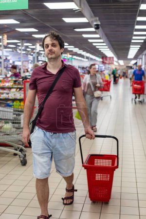 Foto de Hombre feliz llevando carro de compras vacío en el supermercado - Imagen libre de derechos