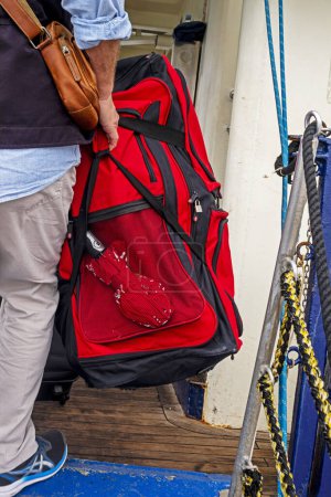 Téléchargez les photos : Passager tient un sac à dos rouge avant le chargement sur le paquebot. Réfugiés, guerre à Izratl et en Ukraine - en image libre de droit