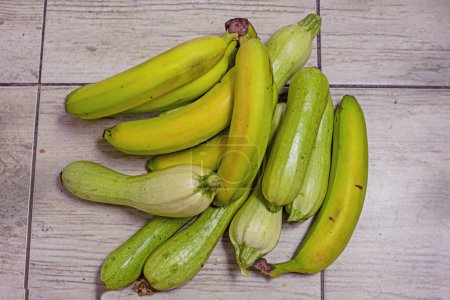 Téléchargez les photos : Bananes vertes se trouvent à côté de courgettes vertes - en image libre de droit