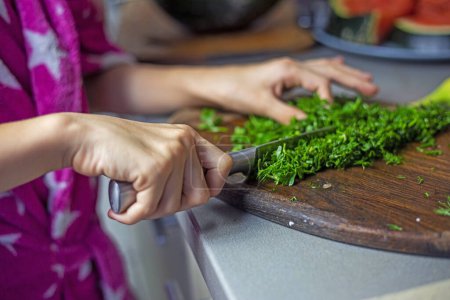 finely chop dill and parsley on a wooden cutting board