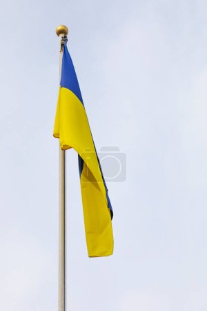 Téléchargez les photos : Drapeau ukrainien sur un mât de drapeau contre un ciel nuageux, avec un accent sur le soutien et les défis de la guerre en Ukraine. - en image libre de droit