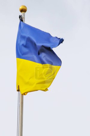 Téléchargez les photos : Drapeau ukrainien sur un mât de drapeau contre un ciel nuageux, avec un accent sur le soutien et les défis de la guerre en Ukraine. - en image libre de droit