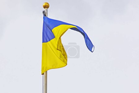 Téléchargez les photos : Drapeau ukrainien sur un mât de drapeau contre un ciel nuageux, avec un accent sur le soutien et les défis de la guerre en Ukraine - en image libre de droit