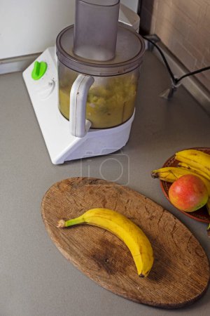 Foto de Machacar plátanos y manzanas en un procesador de alimentos en la cocina - Imagen libre de derechos