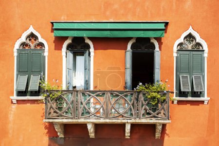 Téléchargez les photos : Belles vieilles fenêtres avec un balcon avec des fleurs fraîches sur un bâtiment à Venise - en image libre de droit