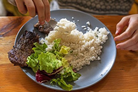 Foto de Niño come arroz con ensalada y tocino a la parrilla. Flatlay. Regreso a la escuela - Imagen libre de derechos